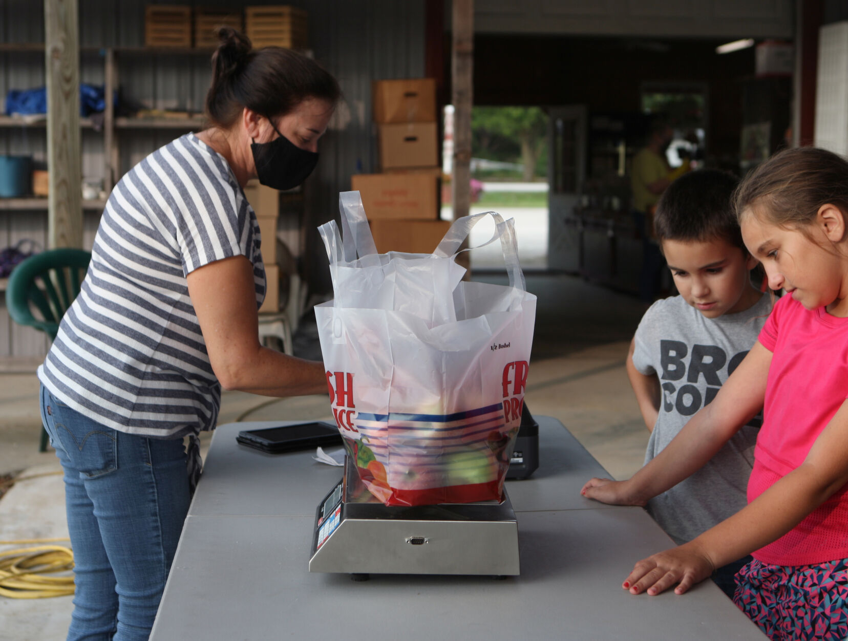Cindy Eckelkamp weighs apples while Logan and Amelia Lewis watch